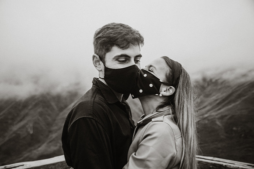 Young couple wearing face masks and kissing during the COVID-19 Coronavirus pandemic