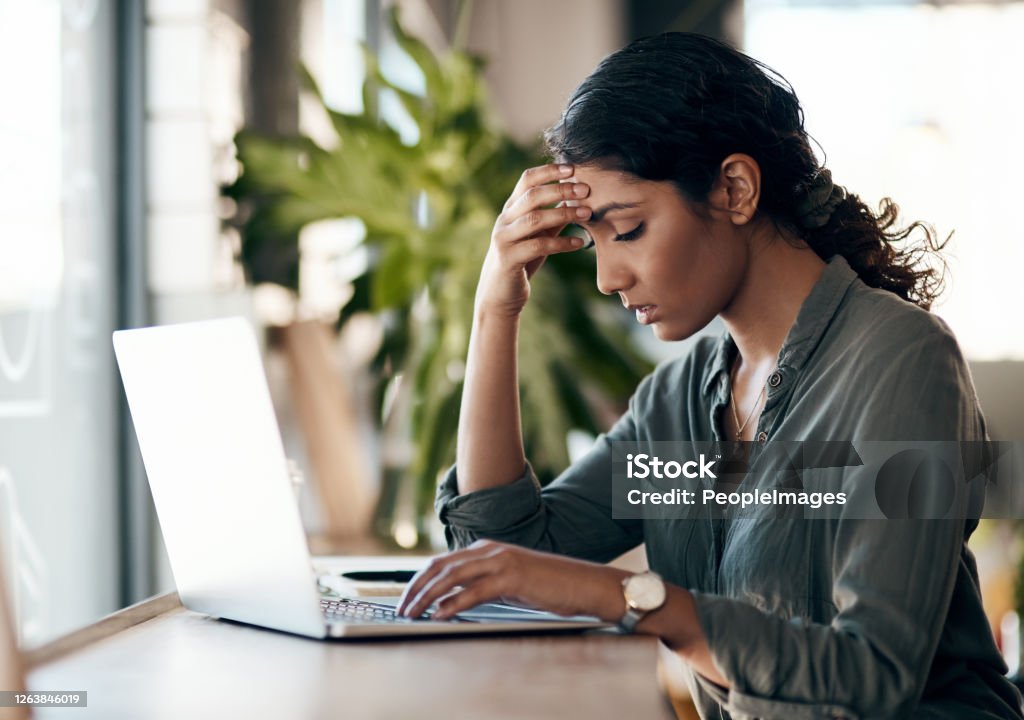 Stress management is a must for solo entrepreneurs Shot of a young woman experiencing stress while working in a cafe Emotional Stress Stock Photo
