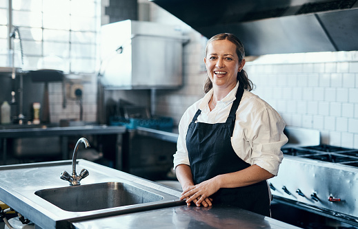 Portrait of a confident mature woman standing in the kitchen of her cafe
