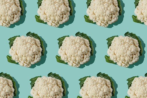 Pattern with cauliflower. Vegetables abstract background. Cauliflower on turquoise blue background.