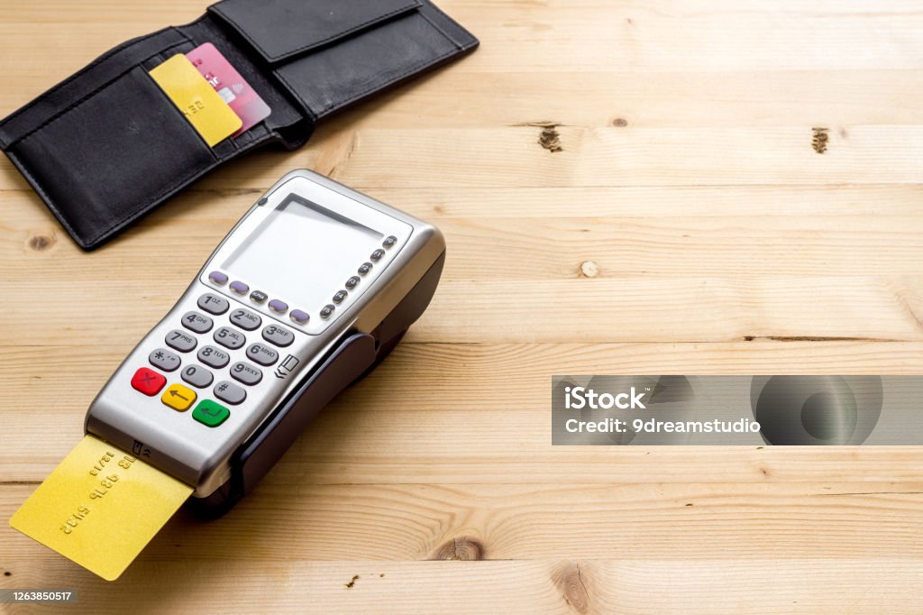 Payment by credit card. Terminal on wooden table copy space Payment by credit card. Terminal on wooden table. Airport Terminal Stock Photo