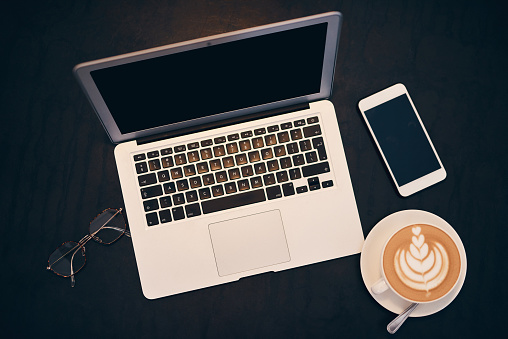 Shot of a laptop, coffee and smartphone on a table in a cafe