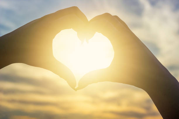 istock fingers folded in a heart on a sunset background 1263851695