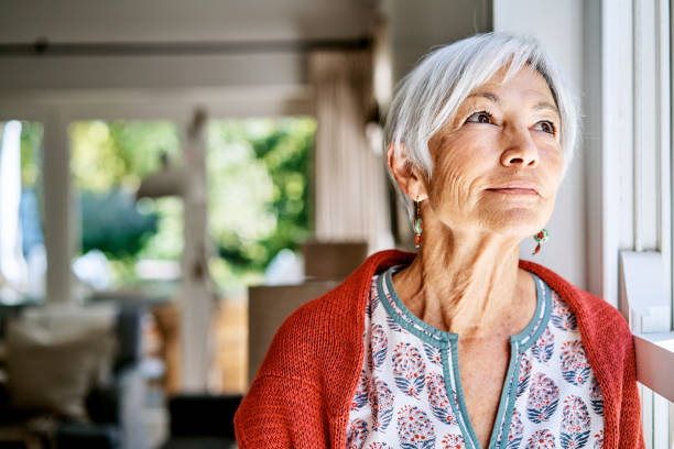 istock Senior woman lost in thought while standing alone at home 1263852401