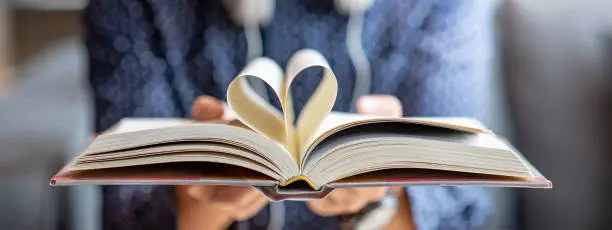 Photo of Male hand holding book with heart shape page folded