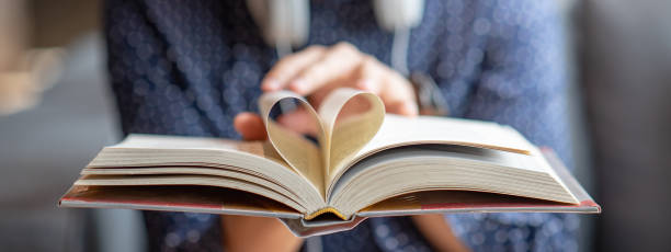 istock Male hand holding book with heart shape page folded 1263852423
