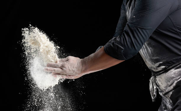 istock chef in black uniform sprinkles white wheat flour in different directions 1263854073