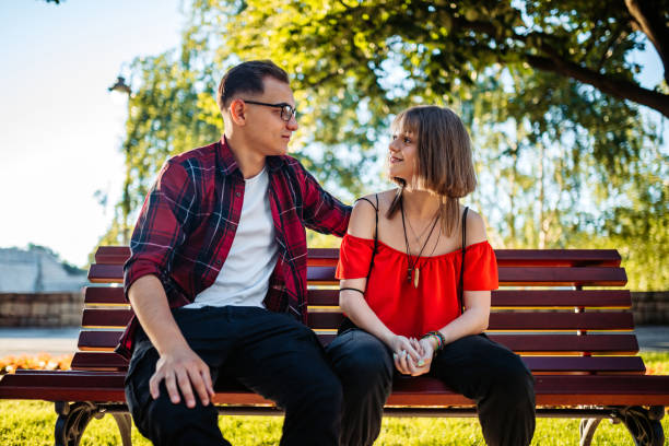 istock Teenage couple siting on park bench 1263855403