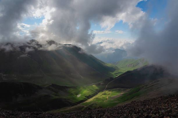 istock Mountain gorge with green meadow illuminated by the sun and blue sky with clouds 1263859156
