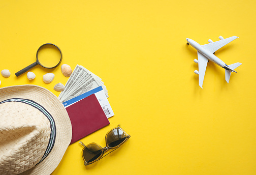 Airplane toy and passport, money, ticket. Travel accessories and objects on a yellow background with a top view and copy space. 
Travel concept background for travel agency banner or poster.