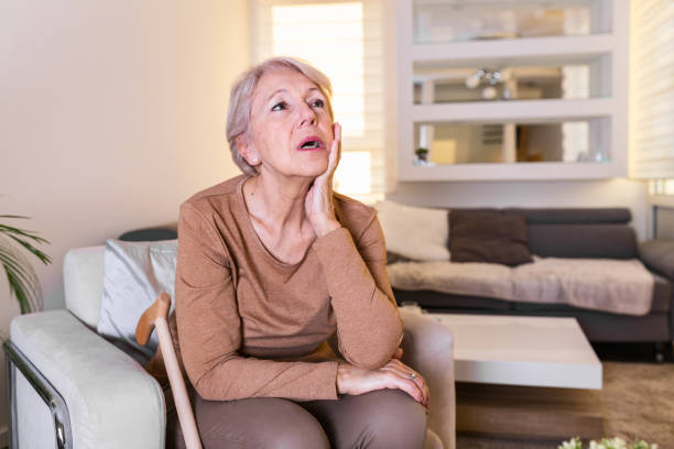 istock Mature woman holding her head with her hands while having a headache and feeling unwell. Senior woman with headache, pain face expression. Elderly woman having head pain migraine 1263861547