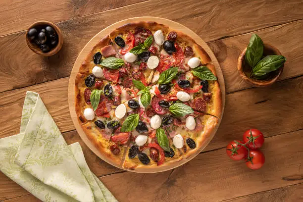 Photo of Pizza and few ingredients on wooden background