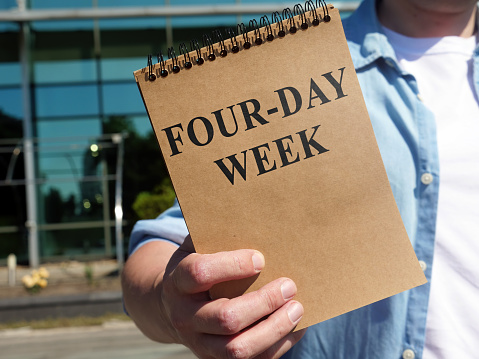 El hombre propone un cartel de cuatro días de la semana. Bloc de notas en la mano. photo