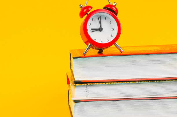 istock books and red clock on yellow background 1263864292