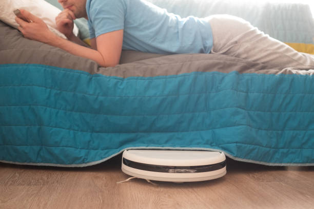 istock Tired man relaxing on sofa with robotic vacuum cleaner on floor 1263865738