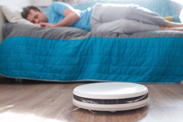 istock Tired man relaxing on sofa with robotic vacuum cleaner on floor 1263865778
