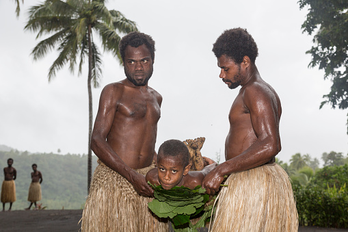 Tanna, Republic of Vanuatu, July 12 2014: Men wear a boy on a stretcher with tree leaves