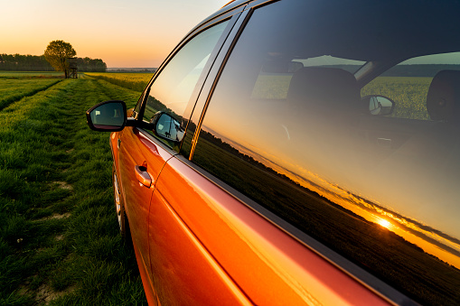 Red car in agricultural field at dawn