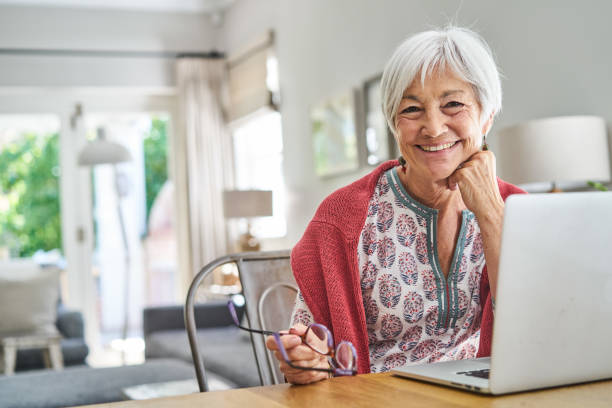istock Smiling senior woman sitting at home using a laptop 1263872704