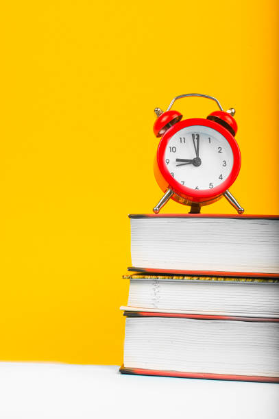 istock books and red clock on yellow background 1263877717
