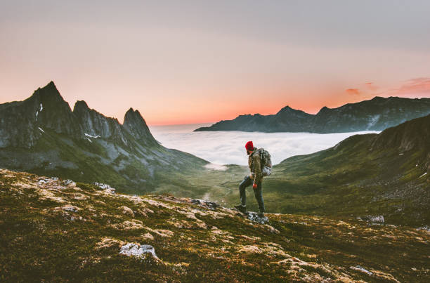 Man backpacker hiking in mountains alone  outdoor active lifestyle travel adventure vacations sunset Norway landscape Man backpacker hiking in mountains alone  outdoor active lifestyle travel adventure vacations sunset Norway landscape senja island photos stock pictures, royalty-free photos & images