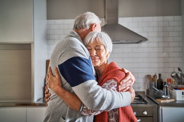 istock Smiling senior woman hugging her husband in their kitchen 1263880386