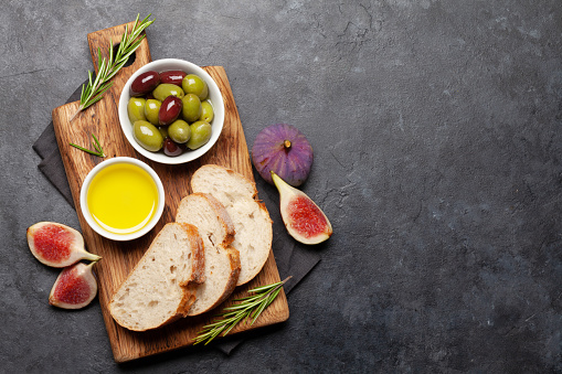 Ripe olives, olive oil, figs and ciabatta bread. Top view flat lay with copy space