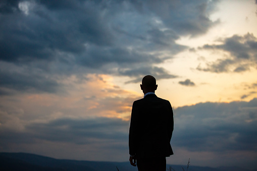Silhouette of mature man, standing back to the camera and looking at dramatic sky