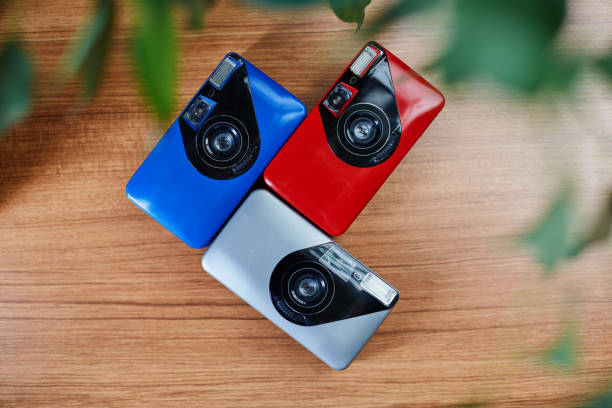 Colorful analog vintage 35mm film cameras lying in arrangement close to each other on a wooden table Colorful analog vintage 35mm film cameras lying in arrangement close to each other on a wooden table point and shoot camera stock pictures, royalty-free photos & images
