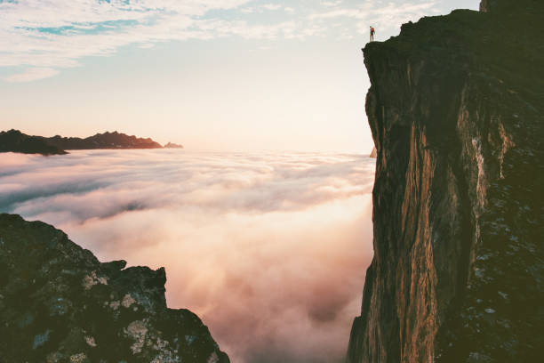 hombre viajero de pie en el acantilado del borde sobre las nubes montañas de la puesta de sol viajan aventura estilo de vida viajes vacaciones en noruega - cliff fotografías e imágenes de stock