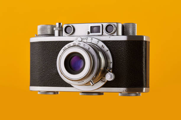 Vintage 35mm rangefinder film camera isolated on yellow / orange colored background Vintage 35mm rangefinder film camera isolated on yellow / orange colored background photographic film camera stock pictures, royalty-free photos & images