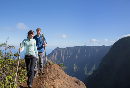 A caucasian couple is hiking on a mountain, taking in a beautiful scenic view.