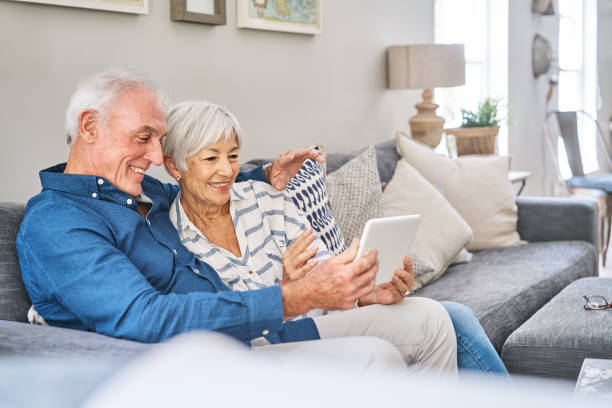 istock Smiling senior couple sitting on their sofa using a digital tablet 1263882541