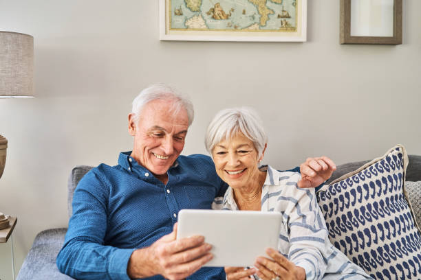 istock Smiling senior couple using a digital tablet in their living room 1263883831