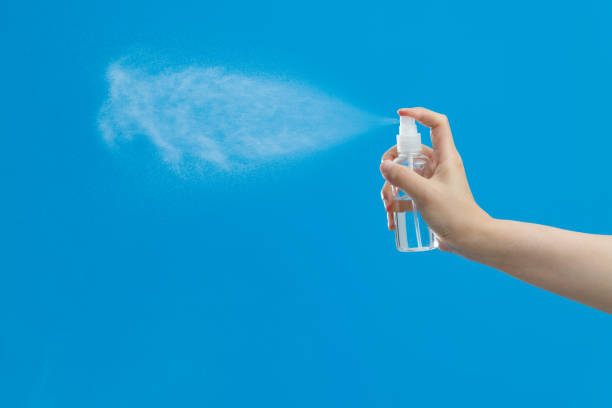 istock Hand holding spray bottle on blue background 1263883832