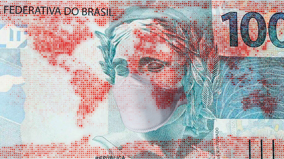 Brazilian real with protective face mask and world map overlay, global economy recession concept