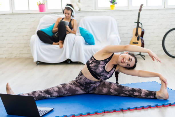 а женщина, которая занимается йогой в гостиной. - the splits flexibility yoga teenage girls стоковые фото и изображения