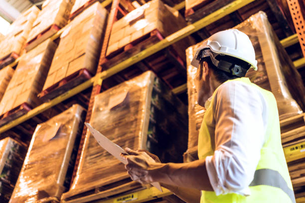 istock Asian man worker holding paper chart checking stock inventory at logistic warehouse storage. side view of male employee working for business export import or shipping company. copy space 1263887929