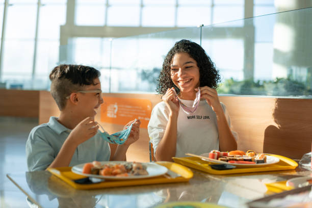 People living the new normal in the coronavirus pandemic Siblings, Smiling, Removing, Protective mask, Lunch no boundary stock pictures, royalty-free photos & images