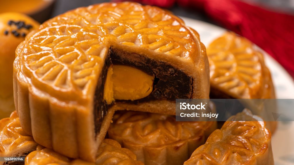 Tasty baked egg yolk pastry moon cake for Mid-Autumn Festival on black slate dark background. Chinese festive food concept, close up, copy space. Moon Cake Stock Photo