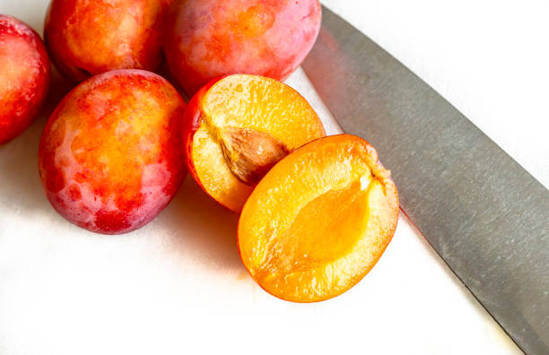 A ripe Victoria plum halved on a chopping board