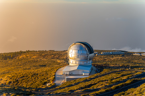 High angle view astronomical observatory on edge of mountain towering over tranquil sea at sunset