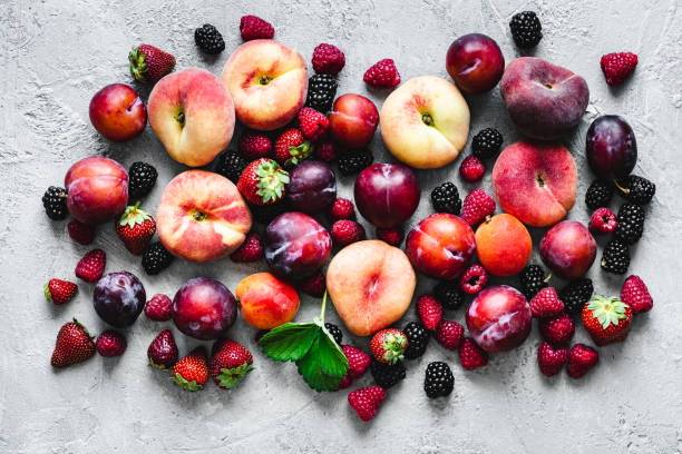 Various types of fruits on white background Top view of various types of tropical fruits on white background. Directly above shot of a blackberries, raspberries, strawberries, plums, peaches, apricots and apples. plum stock pictures, royalty-free photos & images