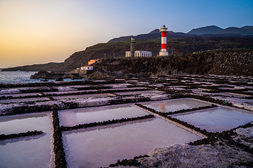 Coast with lighthouse and sea salt evaporation ponds at sunrise