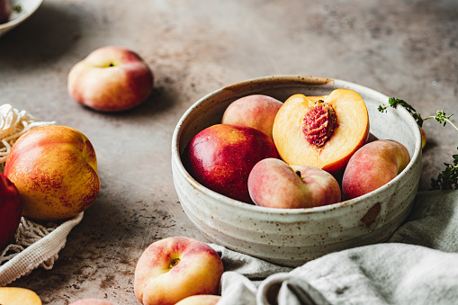 Close-up of ripe peaches in a bowl on kitchen counter.