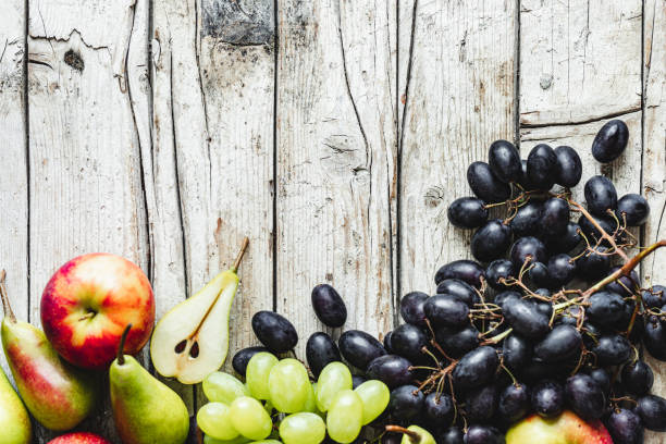 Basket with ripe fruits: apples, pears, grapes, plums close-up selective focus