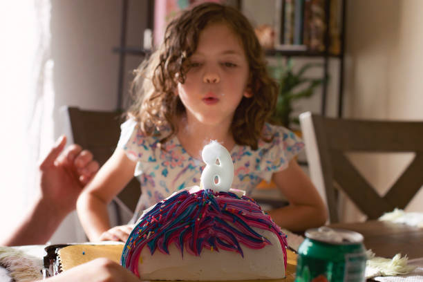 Little girl making a wish while blowing out her birthday candle