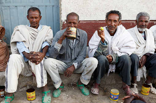 Hamd Ela, Ethiopia, February 23 2015: Ethiopian men sit outside in the street talking and drinking a local drink from old tin cans