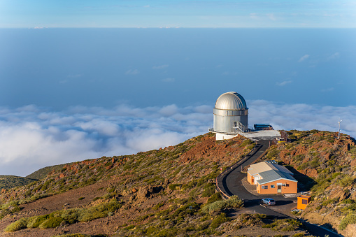 High angle view of astronomical observatory buildings on edge of mountain towering over tranquil blue sea