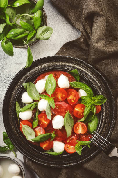 잘 익은 붉은 토마토와 신선한 녹색 바질 잎을 곁들인 모짜렐라 치즈를 곁들인 맛있는 카프레세 샐러드. 이탈리아 음식. 위쪽 보기 - caprese salad heirloom tomato salad food 뉴스 사진 이미지